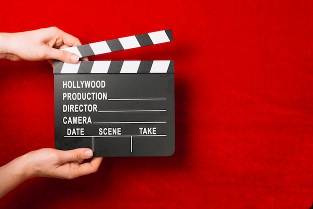 Free photo person holding clapperboard on red background