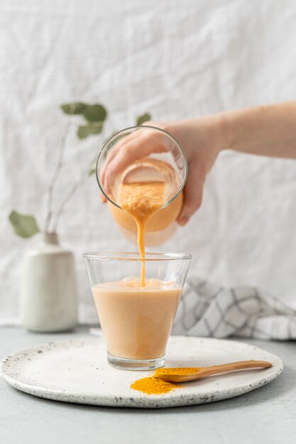 Person holding clear drinking glass with brown juice