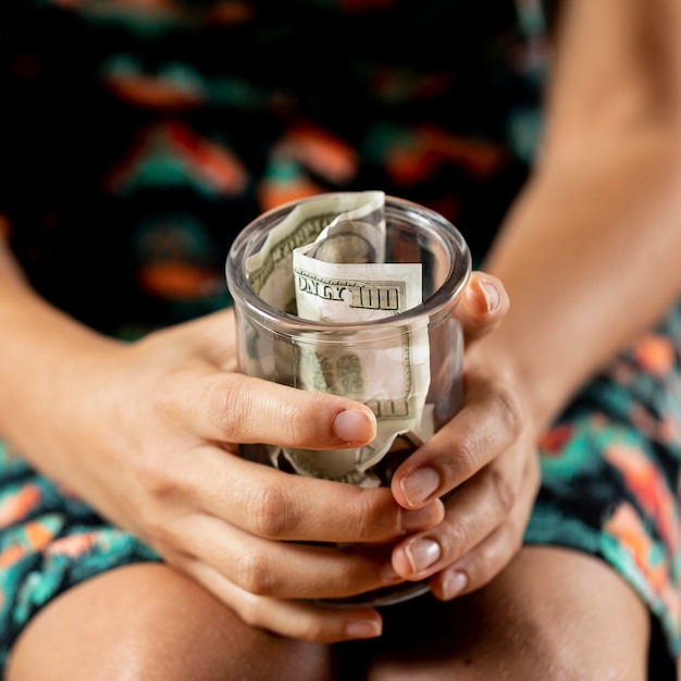 Foto gratuita persona in possesso di vaso trasparente con banconote