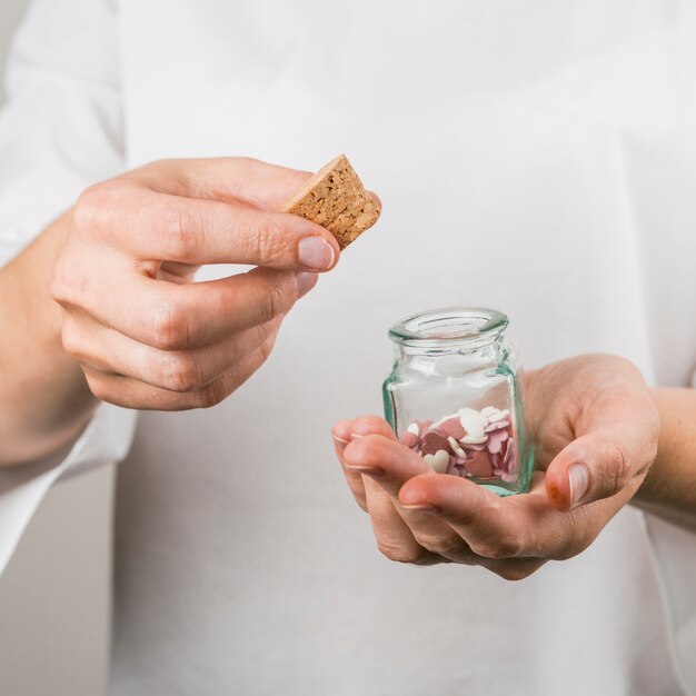 Person holding cork and little jar with decorative hearts 