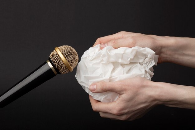 Person holding crumpled paper close to microphone for asmr