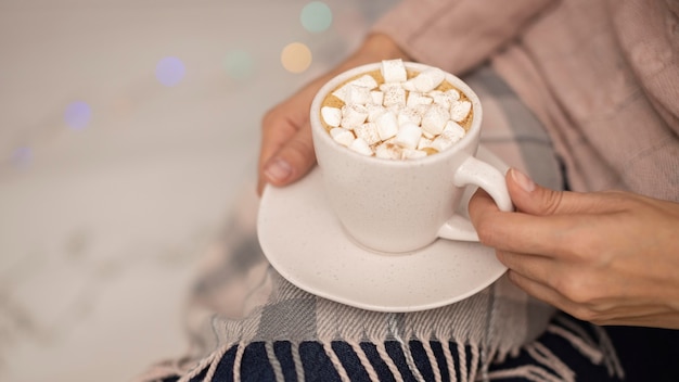 Person holding cup of hot cocoa with marshmallows