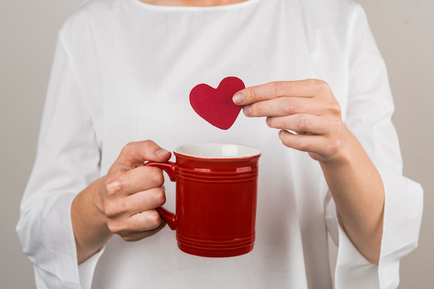 Person holding decorative heart and cup 