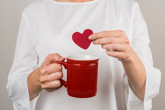 Person holding decorative heart and cup 