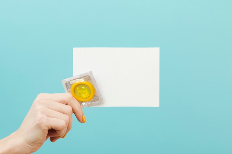 Free Photo person holding an empty card and a condom