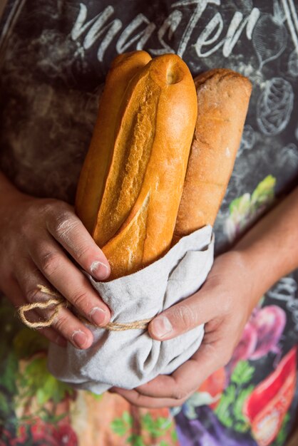 Person holding french baguettes front view