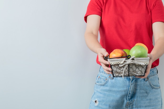 Una persona che tiene in mano un cesto di frutta