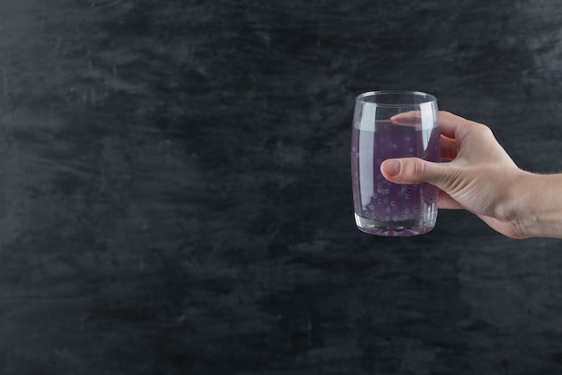 A person holding a glass of purple juice