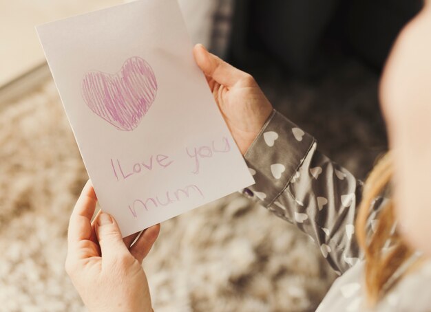 person holding greeting card with i love you mum inscription 