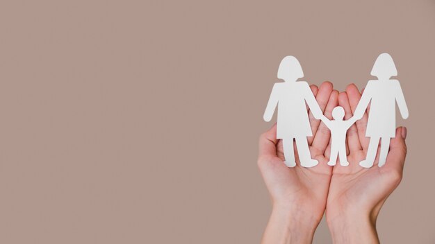 person holding in hands cute paper family with copy space