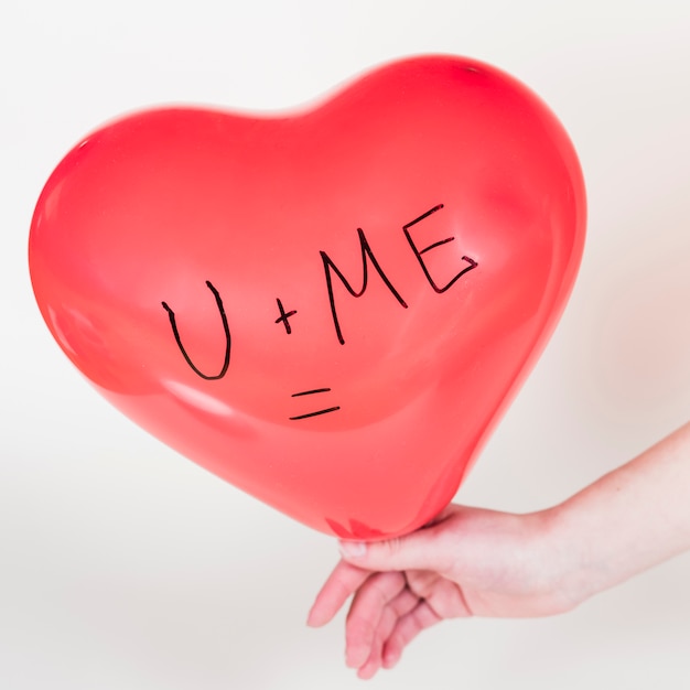 Person holding heart balloon with U + Me = inscription
