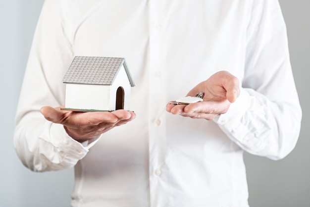 Person holding a house toy and keys
