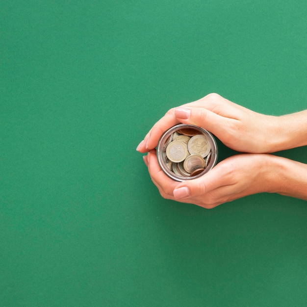 Person holding a jar with coins with copy space