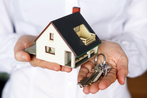 Person holding keys and model house