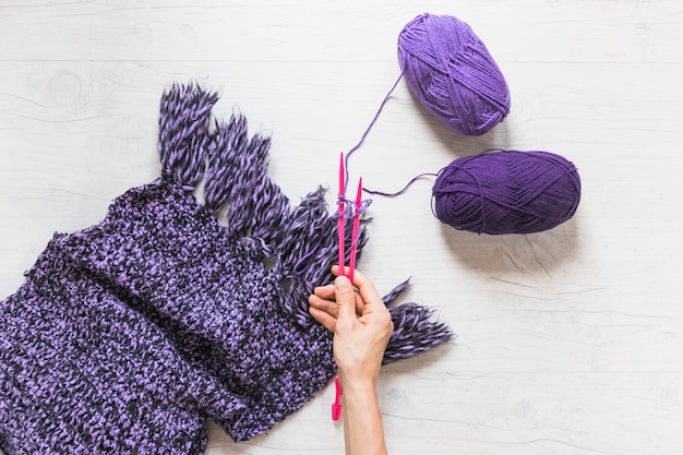 Free photo a person holding knitted needles to knit the woolen scarf