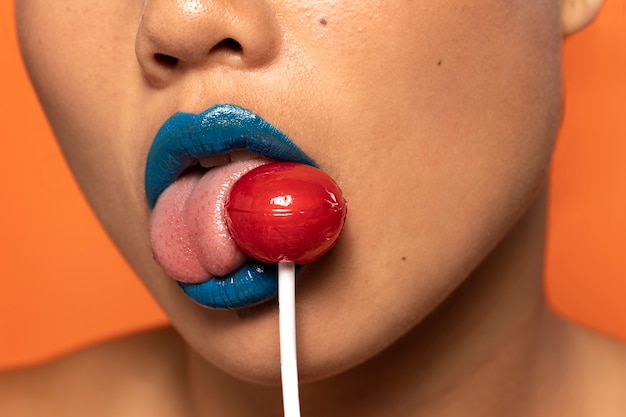 Foto gratuita persona in possesso di caramelle lecca-lecca in bocca
