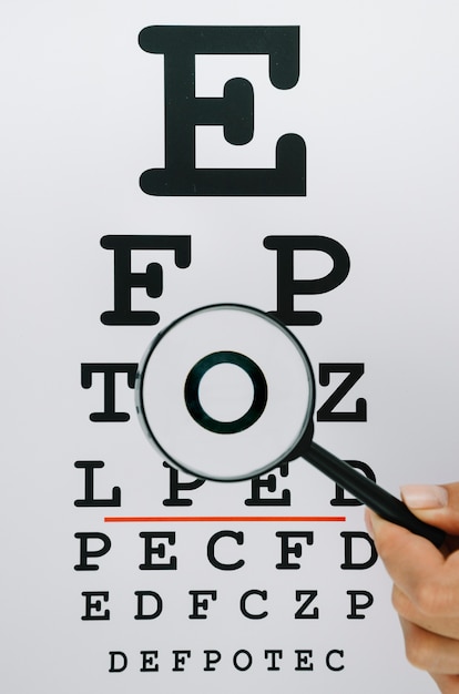 Free photo person holding a magnifying glass over letters