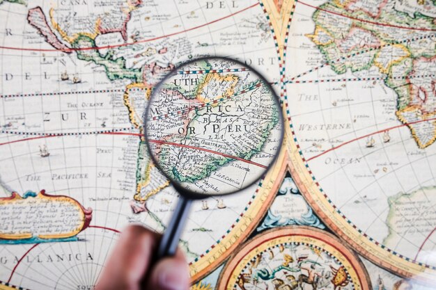 Person holding magnifying glass over map showing Peruvian cities