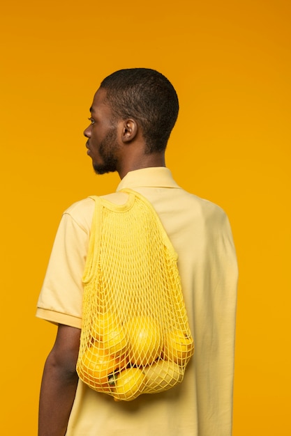 Free photo person holding mesh bag with citrus fruit