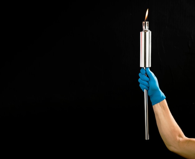 Person holding a metal torch with copy space