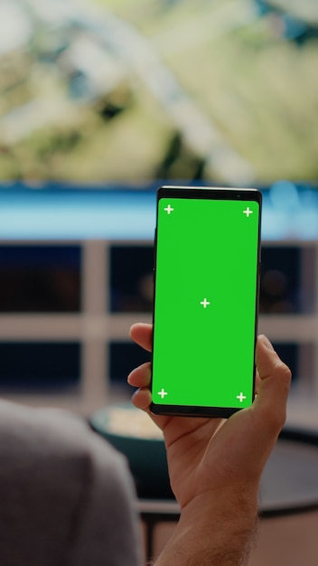 Лицо, занимающее мобильный телефон с зеленым экраном по вертикали