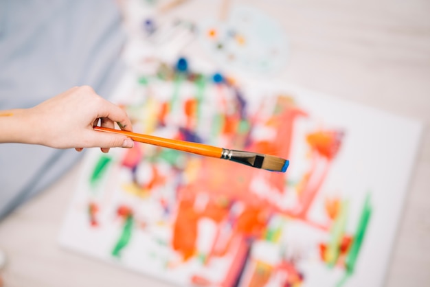 Person holding paint brush above painting
