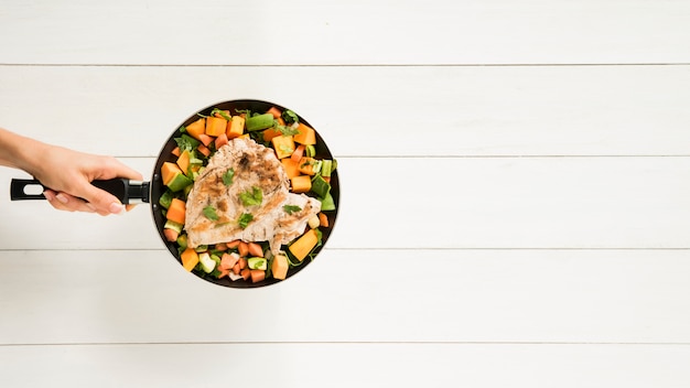 Foto gratuita padella della holding della persona con carne e verdure