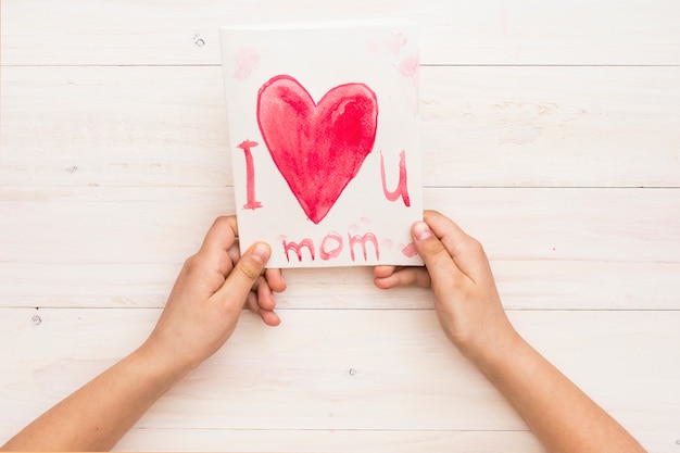 Person holding paper with i love you mom inscription