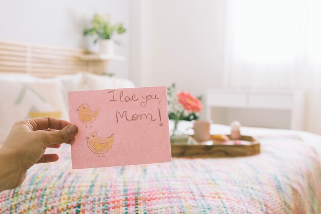 Person holding paper with I love you mom inscription 