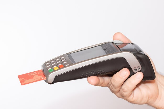빨간 신용 카드로 결제 단말기를 들고있는 사람이 기계를 훑어 보았습니다.