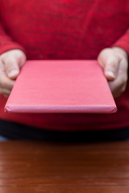 Person holding pink gift box in hands