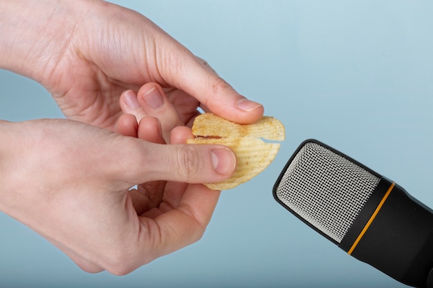 Person holding potato chips close to microphone for asmr