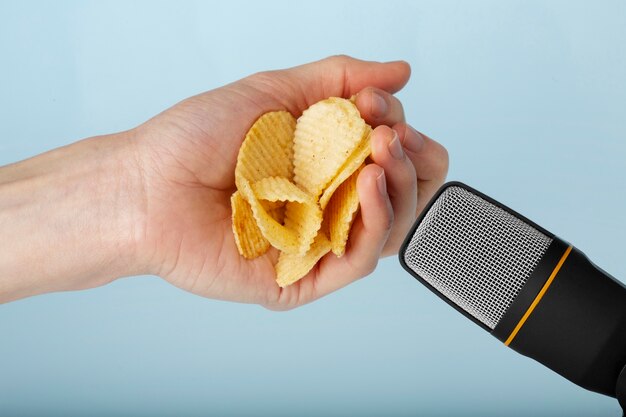 Person holding potato chips close to microphone for asmr