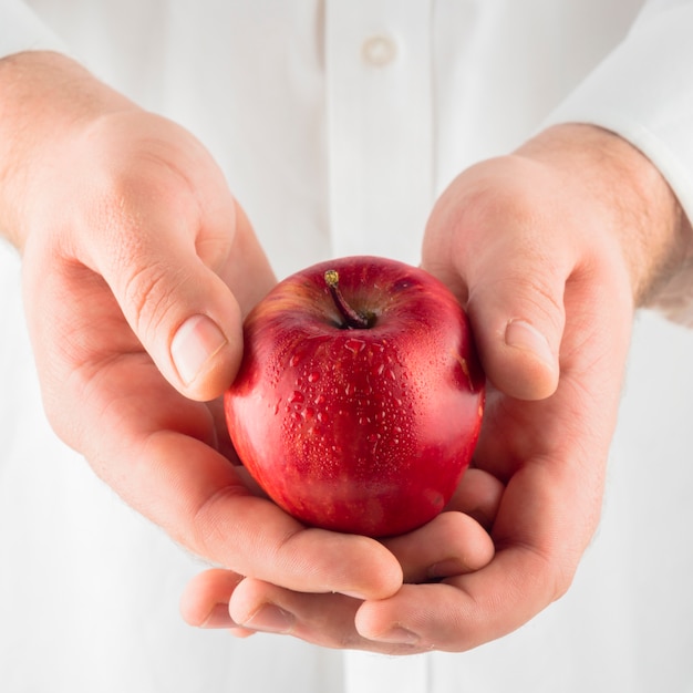 Лицо, занимающее красное яблоко в руках