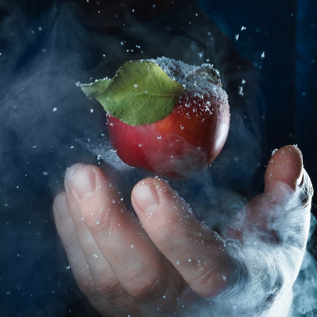 Person holding a red apple with water droplets