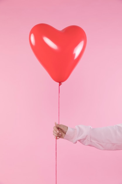 Person holding red balloon with thread