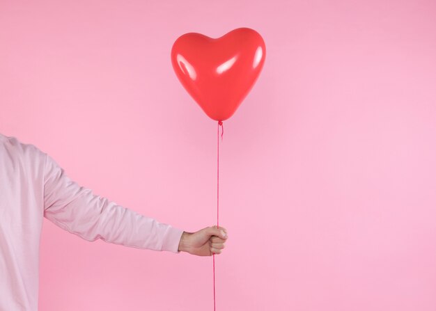 Person holding red balloon with twist