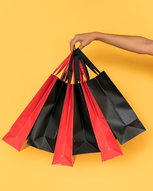 Person holding red and black shopping bags