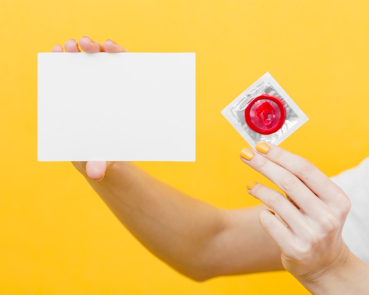 Free Photo person holding a red condom and an empty card