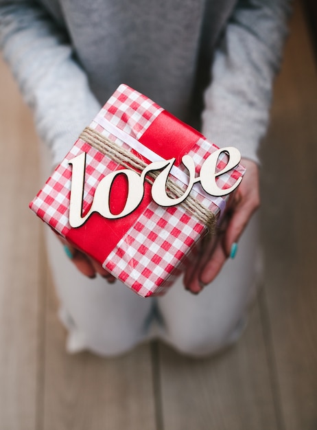 Person holding red gift with word "love"