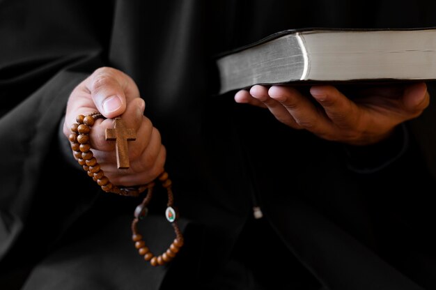 Person holding rosary with cross and holy book