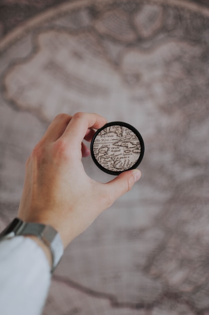 Person holding a round magnifying glass on a blurred globe