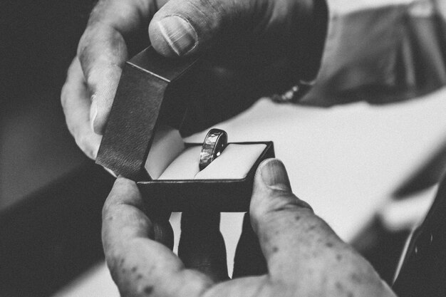 Person holding a silver ring inside of a box
