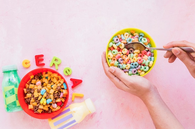 Free photo person holding spoon and bowl near cereal inscription