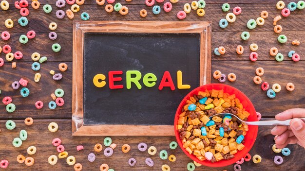 Person holding spoon in red bowl with cereal 