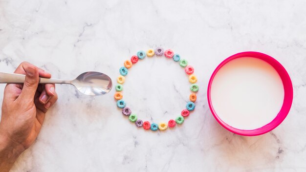 Person holding spoon above table with cereal 