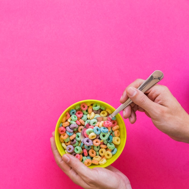 Foto gratuita cucchiaio della tenuta della persona con cereale sopra la ciotola