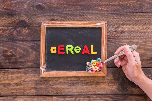 Person holding spoon with cereal above Chalkboard 