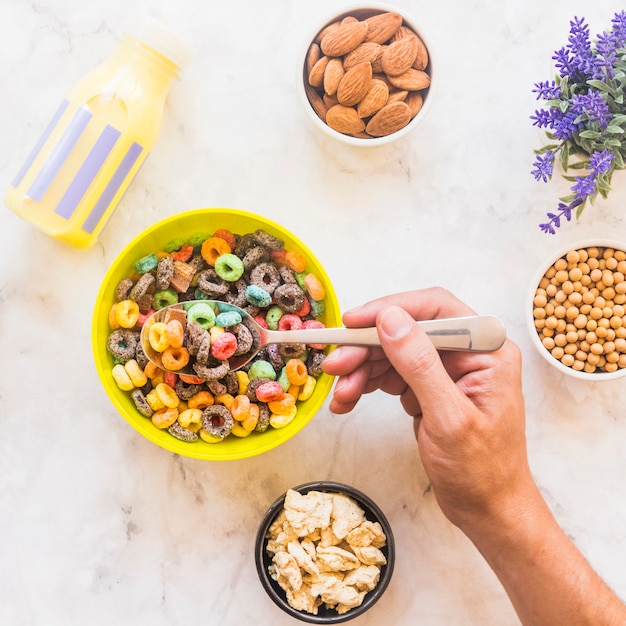 Free photo person holding spoon with cereal above yellow bowl