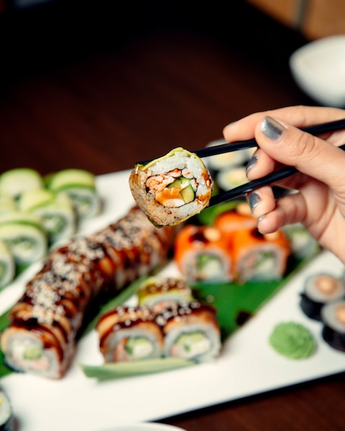 A person holding sushi with sticks